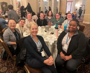 Nine Universities of Wisconsin colleagues seated around a table at the NACADA Region 5 and 6 conference in March 2024 in Milwaukee 