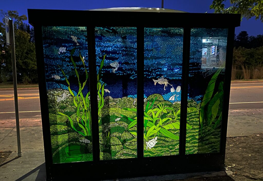 Photo of The six-panel, stained-glass mosaic enclosure was designed by Jyl Kelley, professor of art, and fabricated by art students Theron Christiansen, Erin Phelps and Anmarie “Rie” Roos. 