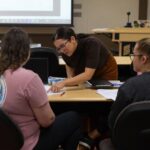 Photo of Assistant Professor Riley Drake, center, with master's students in a practice and theory course / UW-Stout