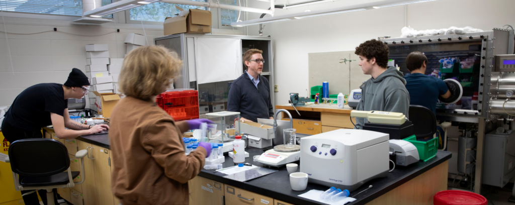 Photo of Steven Girard (center), an associate professor of chemistry at UW-Whitewater, in a university science lab.