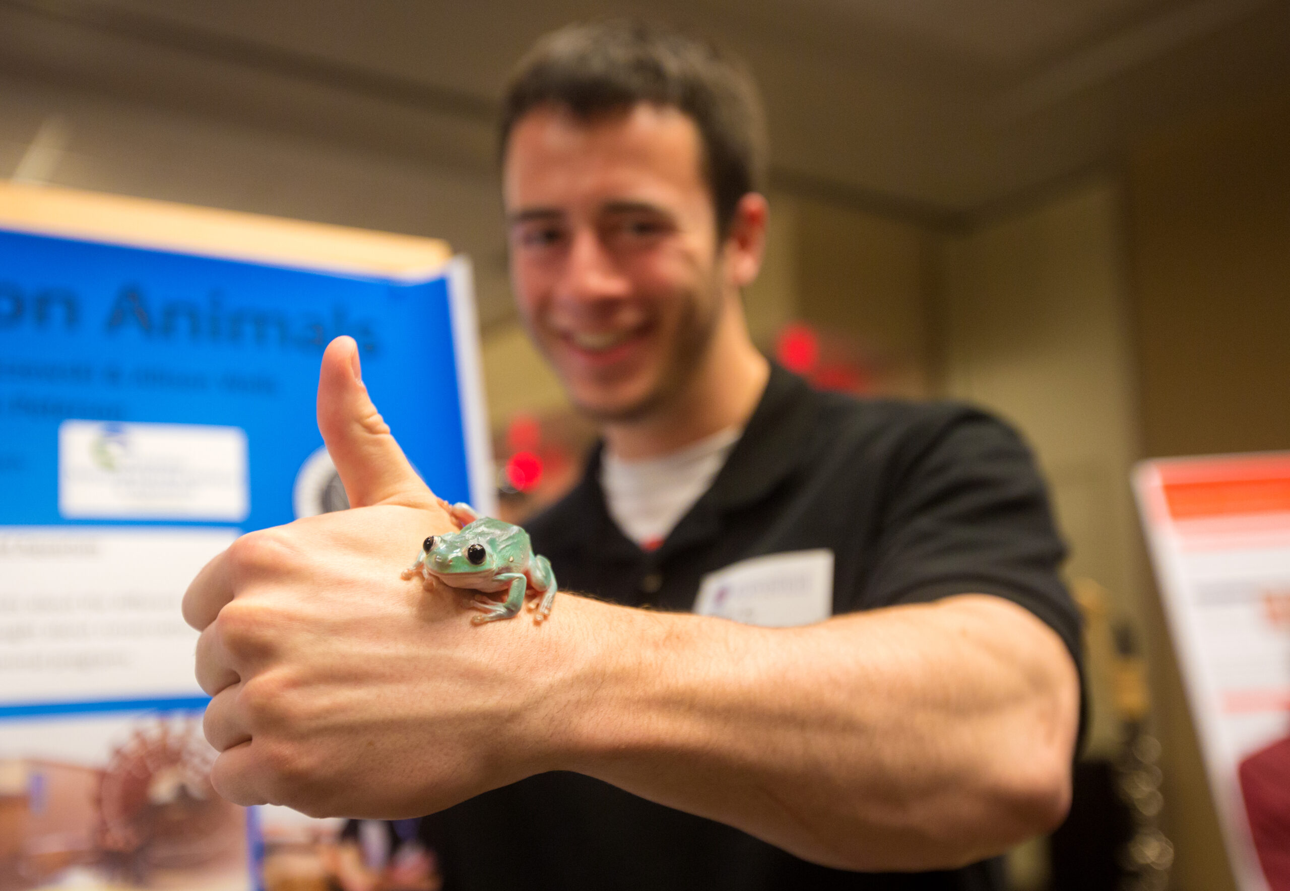 Student presenting poster with frog on hand